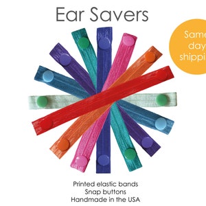 Può includere: Un set di 12 elastici colorati con bottoni a pressione. Gli elastici sono disposti in cerchio con i bottoni rivolti verso l'esterno. Il testo "Ear Savers" è in alto nell'immagine. Il testo "Same day shipping" è in un cerchio giallo in alto a destra dell'immagine. Il testo "Printed elastic bands Snap buttons Handmade in the USA" è in basso nell'immagine.