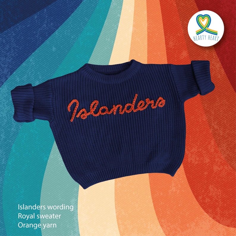 Puede incluir: Un su&eacute;ter azul marino de manga larga con la palabra Islanders bordada en hilo naranja en el pecho. El su&eacute;ter tiene un cuello redondo acanalado y pu&ntilde;os acanalados en las mangas. El texto Islanders est&aacute; escrito en un estilo de letra cursiva.