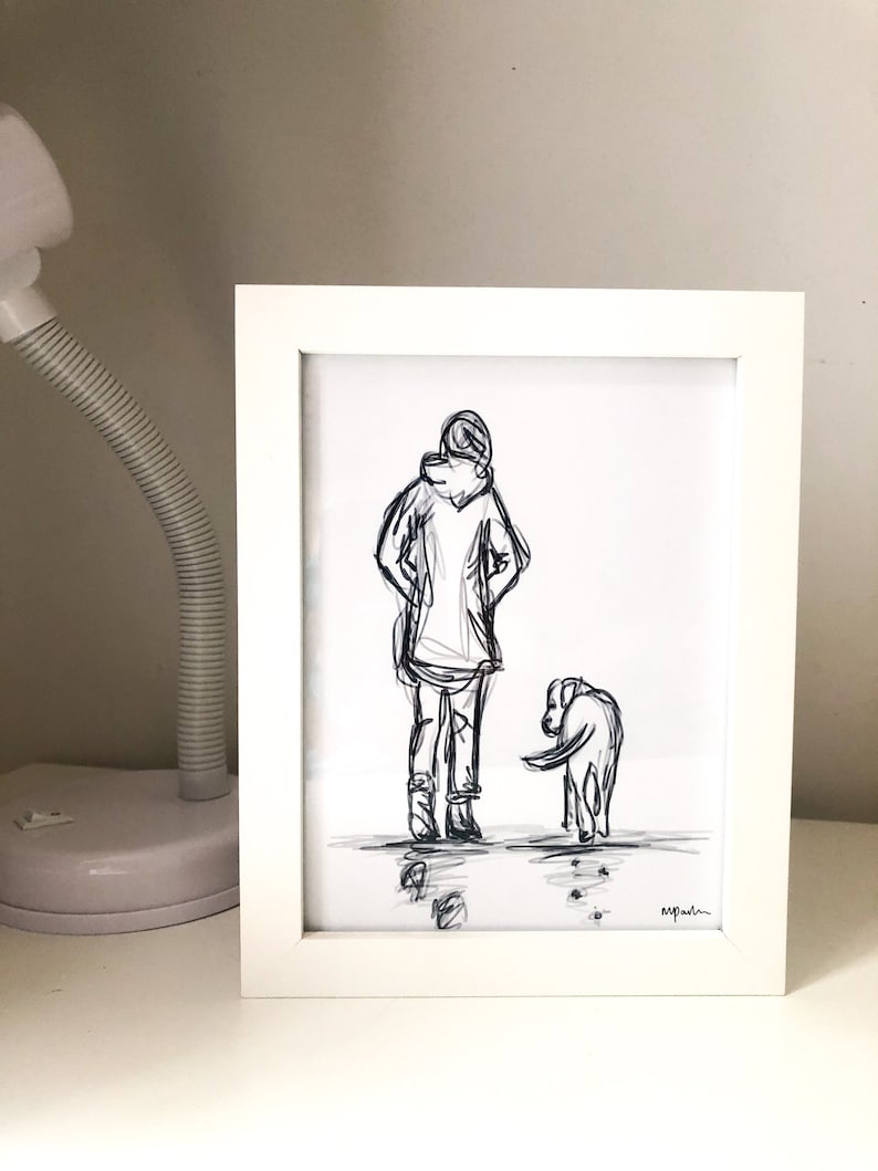 Op de afbeelding: Een zwart-wit schets in een witte lijst van een persoon met een hond. De persoon draagt een jas met capuchon en een broek. De hond kijkt naar de grond. De tekening is in een witte lijst.