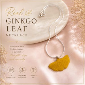 May include: A silver-toned chain necklace featuring a single, textured, mustard-yellow ginkgo leaf pendant. The text on the image reads: Real GINKGO LEAF NECKLACE, Made with real Ginkgo leaves — a symbol of strength, hope and serenity, REAL GINKGO LEAF, HANDMADE WITH LOVE, PERFECT GIFT.