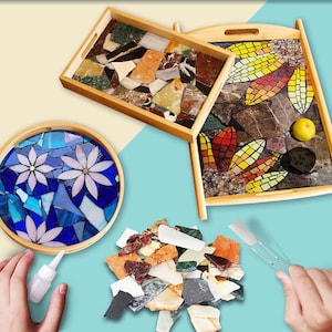 May include: Wooden serving trays with mosaic tile designs. One rectangular tray features a mosaic of colorful stone pieces. Another rectangular tray has a leaf-like mosaic. A round tray displays a blue floral mosaic.
