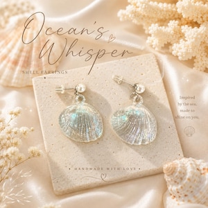 May include: A pair of dangle earrings featuring iridescent, glittery seashell charms suspended from small silver-toned posts with white spherical beads. The text Ocean's Whisper, SHELL EARRINGS, and HANDMADE WITH LOVE is printed on the display card.