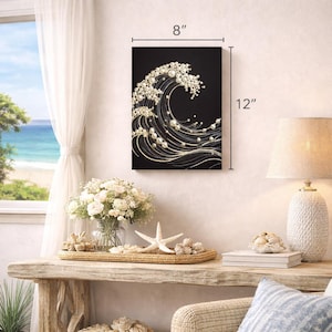 May include: A black canvas art piece depicting a wave design, embellished with white pearls and gold accents. The artwork measures 8 inches wide and 12 inches high. The wave design is a decorative element for coastal or nautical themed decor.