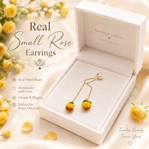 Op de afbeelding: Real Small Rose oorbellen in een witte doos. De oorbellen hebben kleine, gedroogde gele en rode rozen die aan een gouden ketting hangen. De doos is gevoerd met crèmekleurige stof en heeft de tekst "Handmade with love JUST FOR YOU".