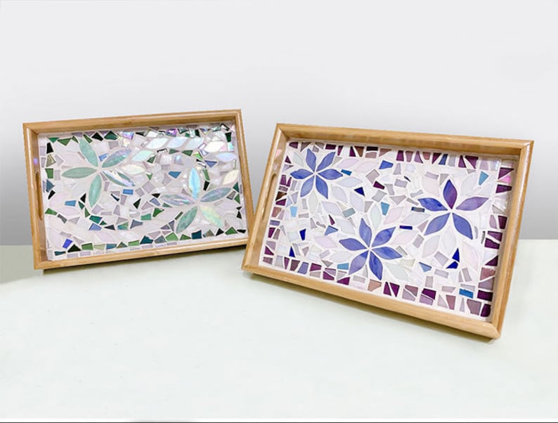 May include: Two rectangular mosaic trays with wooden frames. One tray features light green and blue floral designs, while the other showcases purple and blue flowers. Both have a mosaic tile background.