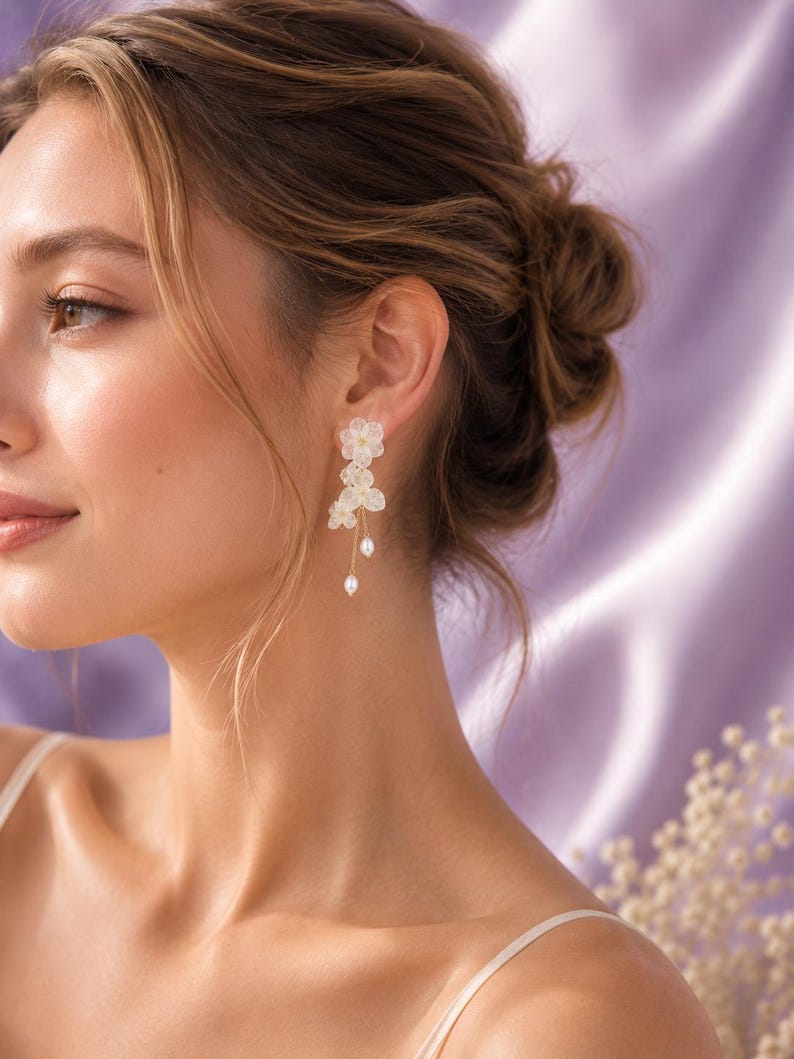 May include: Dangle earrings featuring layered white translucent flower petals and small dangling white pearls suspended from thin gold-toned metal chains. The floral design consists of multiple stacked petals with a delicate, lightweight appearance.