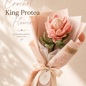 May include: A single crocheted King Protea flower with pink petals and green leaves, wrapped in light pink paper with a ribbon and a tag that reads Especially for you. The text Handmade Crochet King Protea Flower is visible.