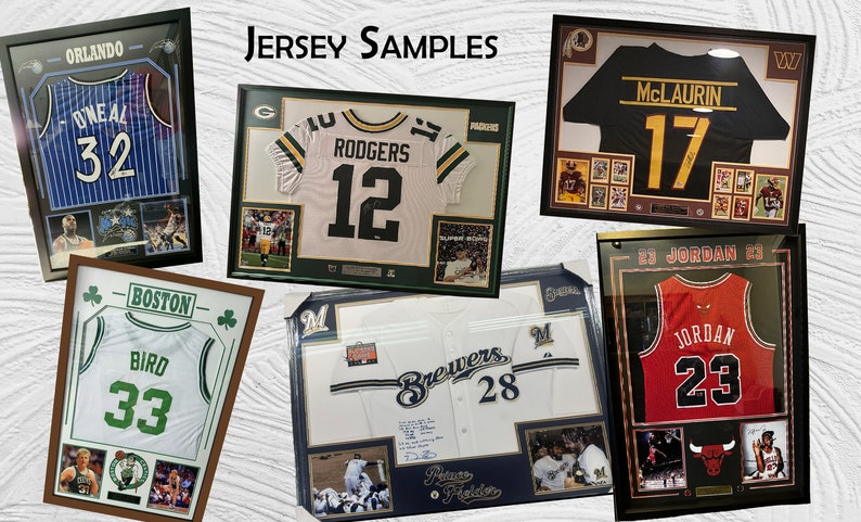 May include: A collection of framed sports jerseys, including a white jersey with the number 12 and the name "RODGERS" in green and yellow, a black jersey with the number 17 and the name "McLAURIN" in yellow, a red jersey with the number 23 and the name "JORDAN" in black, a white jersey with the number 33 and the name "BIRD" in green, a white jersey with the number 32 and the name "O'NEAL" in blue, and a white jersey with the number 28 and the name "Brewers" in blue.