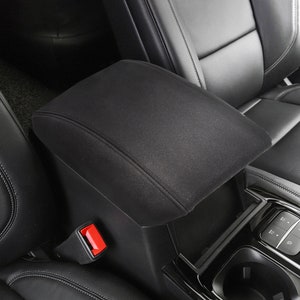May include: Black car armrest cover with a red button. The armrest is made of a soft, plush material and has a built-in storage compartment.