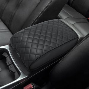 May include: Black quilted leather car armrest cover. The cover is designed to fit over the existing armrest and provides a more comfortable and stylish look.
