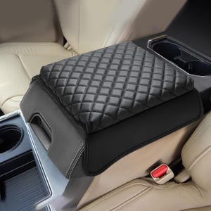 May include: Black quilted armrest cover for a car. The cover is made of a soft, durable material and has a diamond-stitched pattern.