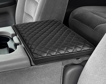 May include: Black quilted leather car seat cushion. The cushion is designed to fit over the center console of a car.