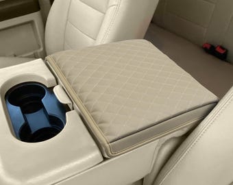May include: Beige quilted armrest cover for a car. The cover has a diamond pattern and is made of a soft, durable material.