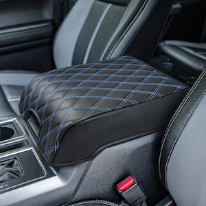 May include: Black leather center console armrest cover with blue diamond stitching. The cover is designed to fit a vehicle's center console.