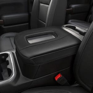 May include: Black leather center console armrest with a storage compartment and cup holders in a car interior.