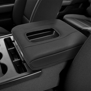 May include: Black leather car console armrest with a built-in storage compartment. The armrest has a rectangular shape with a stitched design and a recessed handle. The console is installed in a vehicle interior.