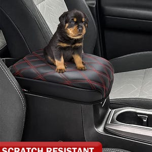 Peut inclure: Housse de repose-bras de si&egrave;ge de voiture noire et rouge avec un motif en losange. La housse est con&ccedil;ue pour prot&eacute;ger le repose-bras des rayures caus&eacute;es par les animaux domestiques ou les objets pointus. "R&eacute;sistant aux rayures" est &eacute;crit en rouge sur fond blanc.