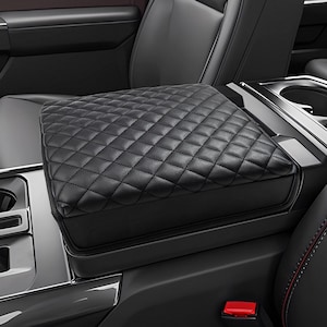 May include: Black quilted leather center console armrest cover for a car. The cover is made of soft, durable material and provides a comfortable resting place for your arm.