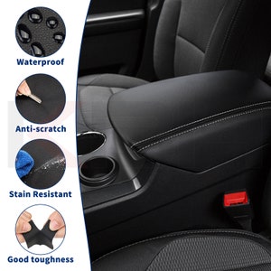 May include: Black car armrest with white stitching, cup holders, and a red seat belt buckle. The image also shows close-ups of the material, highlighting its waterproof, anti-scratch, stain-resistant, and durable qualities. Text on the image reads: Waterproof, Anti-scratch, Stain Resistant, Good toughness.