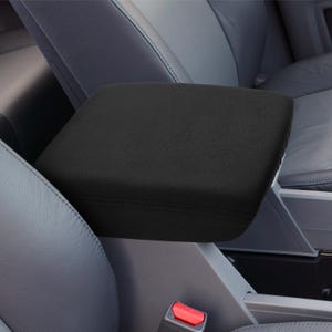 May include: Black armrest cover for a car seat. The cover is made of a soft, plush material and has a simple design.