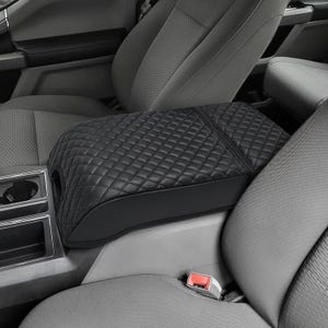 May include: Black quilted leather center console armrest cover for a car. The cover is designed to fit snugly over the existing armrest and provides a comfortable and stylish upgrade to the interior.