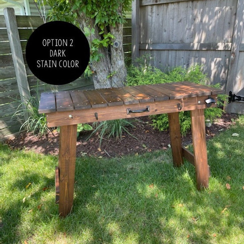 Pu&ograve; includere: Un tavolo in legno scuro con un aspetto rustico. Il tavolo ha un unico cassetto con una maniglia nera ed &egrave; sostenuto da due gambe a forma di A. Il testo "OPTION 2 DARK STAIN COLOR" &egrave; visibile nell'immagine.