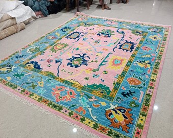 May include: A pink, blue, green, and yellow patterned rug with a floral design. The rug has a fringed edge.