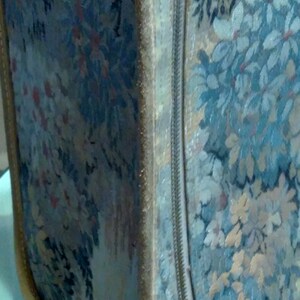 May include: A vintage floral patterned suitcase with a zipper closure and a gold metal latch. The suitcase is made of a soft, textured fabric.