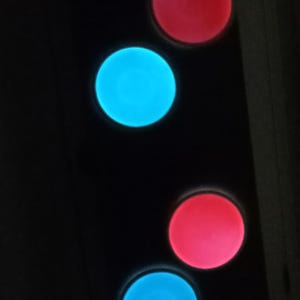 May include: Five round, glowing buttons in different colors. The buttons are arranged vertically, with a blue button at the top, followed by a red button, then a blue button, then a red button, and finally a pink button at the bottom.