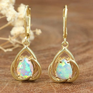 May include: A pair of gold earrings with a pear-shaped opal gemstone in each. The earrings have a delicate, intricate design.