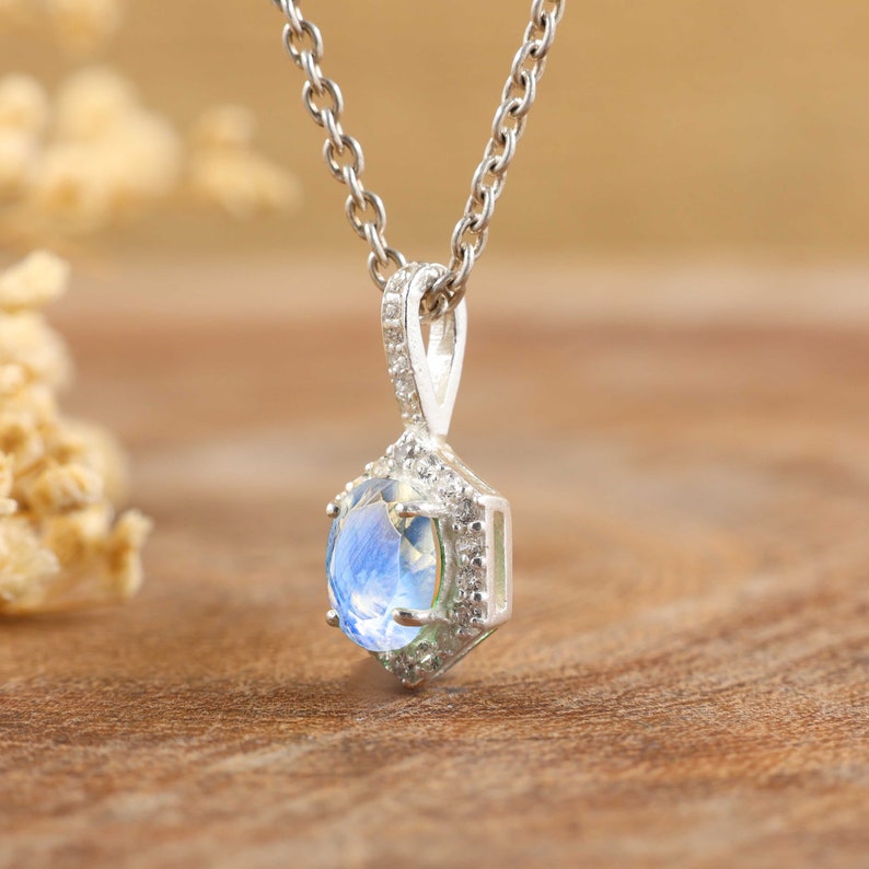 Pu&ograve; includere: Una collana d'argento con un ciondolo di pietra blu circondato da pietre trasparenti pi&ugrave; piccole.