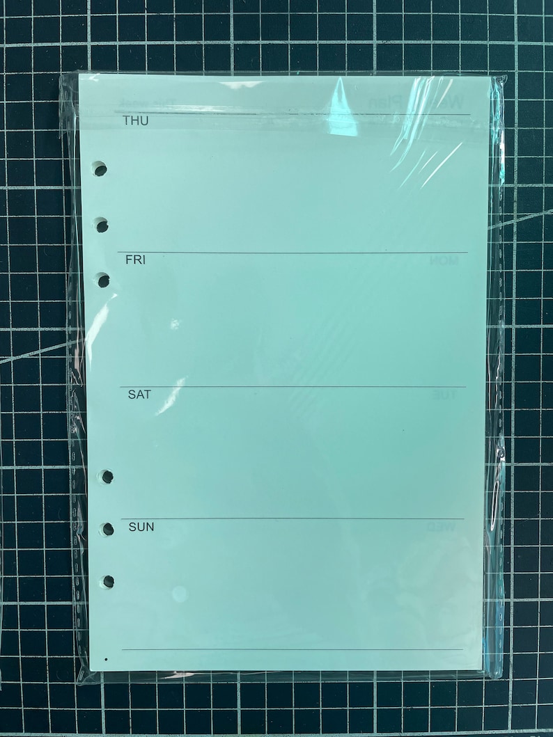 May include: A light green weekly planner page with a plastic cover. The page has four sections labeled "THU", "FRI", "SAT", and "SUN".