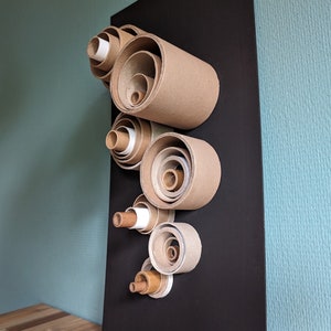 Obra de arte reciclada: cartón, tubos de papel sobre pizarra mate, círculos.