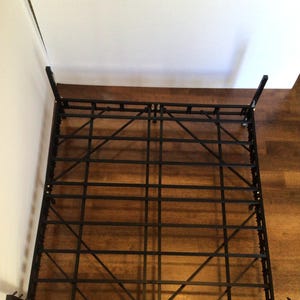 Puede incluir: Estructura de cama de metal negro con un sistema de soporte de listones. El marco está diseñado para sostener un colchón y un somier.