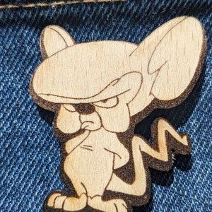 May include: A wooden cutout of a cartoon character with large ears and a mischievous expression. The character is brown and has a white outline. The character is standing on its hind legs with its front paws crossed.