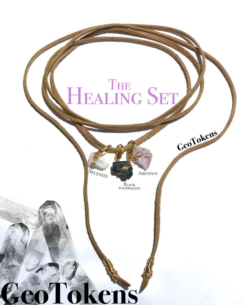 K&ouml;nnte beinhalten: Das Healing Set von GeoTokens besteht aus einem braunen Lederband mit vier Kristallanh&auml;ngern: Selenit, Amethyst, schwarzer Turmalin und einem vierten Kristall. Das Band ist an den Enden mit Golddraht umwickelt.