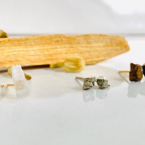May include: Three pairs of earrings with different crystal styles. The first pair is white, the second pair is silver, and the third pair is brown.