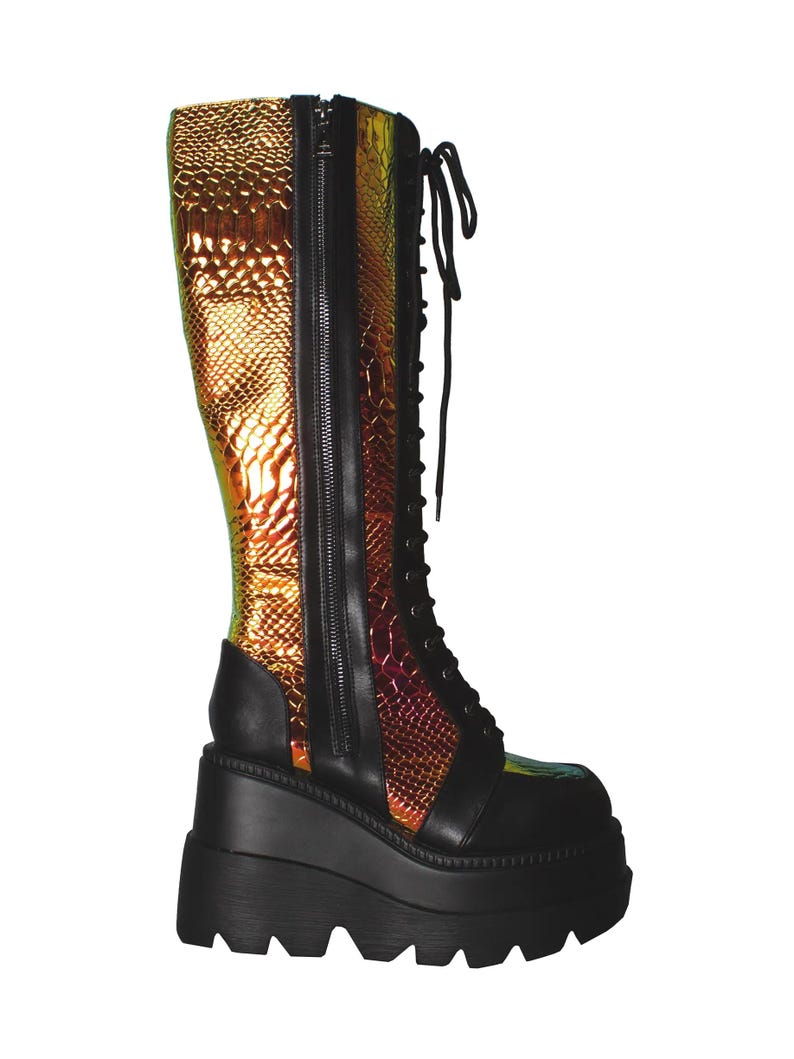 May include: A knee-high platform boot featuring a black matte base with a thick, lugged sole. The upper combines black panels with iridescent, metallic gold and copper snakeskin-textured material, finished with black laces and a side zipper.