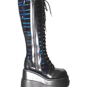 May include: A knee-high boot featuring a black iridescent shaft with a blue and purple sheen, a full-length side zipper, and black laces. The boot is set on a thick, chunky black platform wedge sole with a textured, lugged bottom edge.