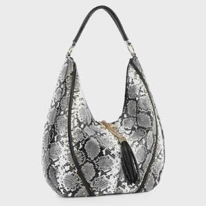 May include: A hobo-style handbag featuring a black and white snakeskin pattern. The bag has a single black shoulder strap attached with silver-tone metal rings, black piping accents, and a decorative black tassel hanging from the center front.