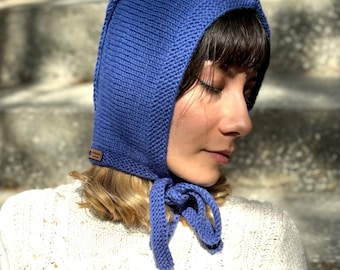 May include: A blue knitted hat with a long pointed hood and a tie at the back. The hat is made of a soft, warm material and is perfect for keeping your head and ears warm in the winter.