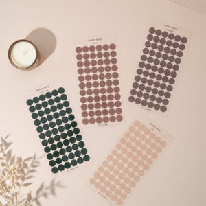 May include: Four sheets of sticky dots in different colours: dark green, brown, grey, and beige. Each sheet has 60 dots.