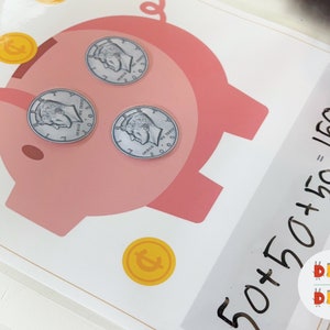 May include: A pink piggy bank with three silver coins inside. The coins are US nickels with the text "LIBERTY" and "IN GOD WE TRUST". The piggy bank has a black line drawn on it and the text "50+50+50=150 cents" is written on a white background.