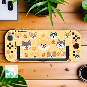 May include: Yellow game console cover featuring a repeating pattern of cartoon dog faces and paw prints. The cover has buttons and joystick controls on the sides. The text "OK play" is visible on the bottom left.