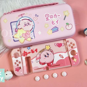 Może przedstawiać: Różowe etui transportowe do Nintendo Switch z wzorem różowego i białego Kirbyego. Etui ma zamek błyskawiczny i uchwyt. Etui jest otwarte i pokazuje wnętrze etui, które również jest różowe i ma wzór Kirbyego. Etui leży na różowej powierzchni.