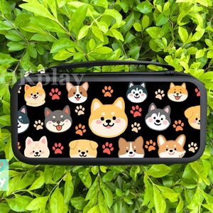 May include: Black carrying case with a repeating pattern of cartoon dog faces and paw prints. The dogs are various breeds, including Shiba Inus and Huskies. The case has a black handle and a zipper. The text "Kplay" is visible on the top left.