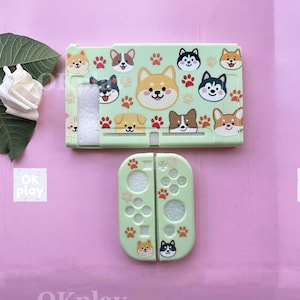 May include: A light green Nintendo Switch case and controller covers featuring a repeating pattern of cartoon dog faces and paw prints. The case and controller covers are made of plastic.