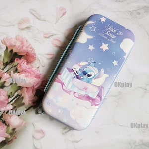 May include: A blue and purple Nintendo Switch case featuring a Stitch and Scrump design. The case depicts a cartoon image of Stitch and Scrump flying in a box with stars and a moon in the background. The text "Stitch & Scrump" and "Dreams & Family" is printed on the case.