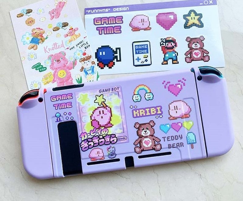 May include: A purple Nintendo Switch console with a custom design featuring pixelated characters, hearts, and the text "GAME TIME", "KRIBI", and "TEDDY BEAR".