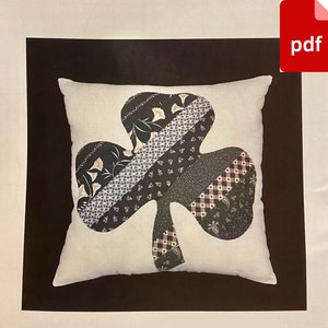 May include: A white pillow with a black and white shamrock design. The shamrock is made of fabric scraps in various patterns.